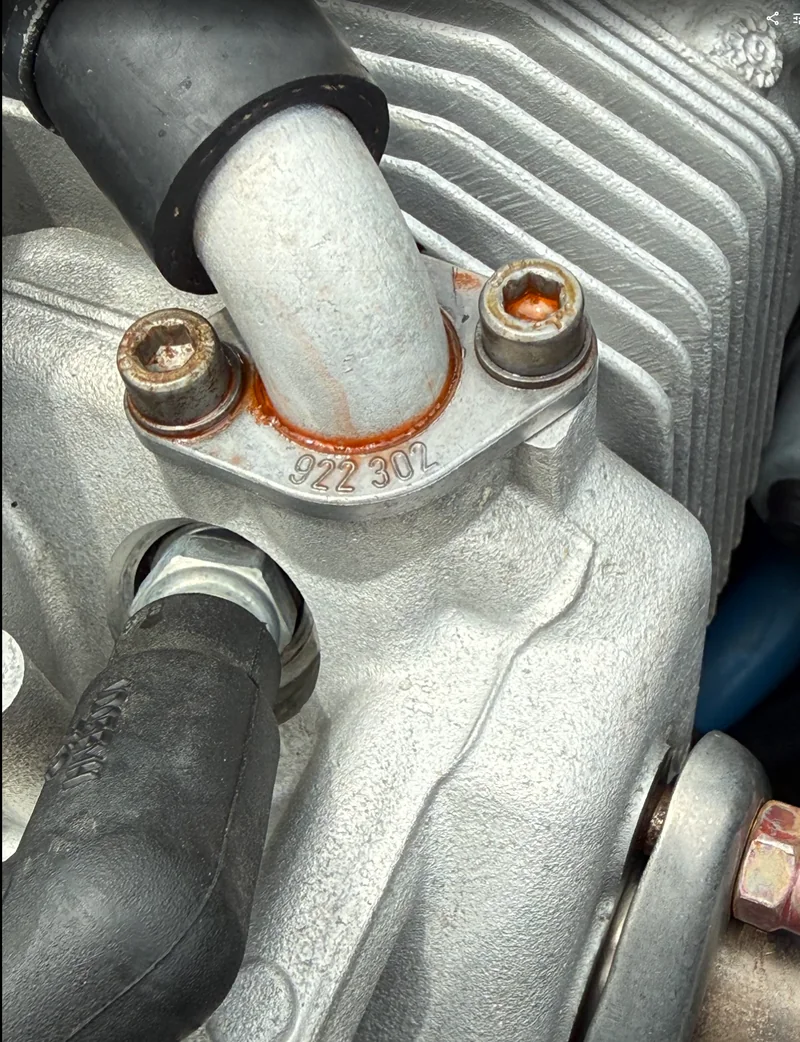Orange coolant residue around a ROTAX coolant fitting and cylinder head area