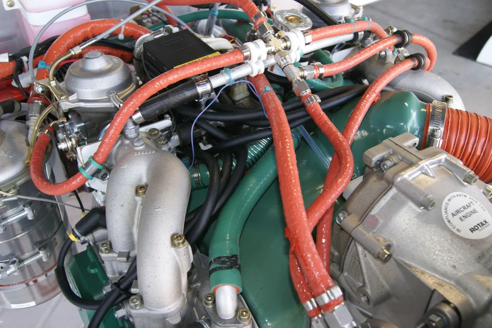 Installed ROTAX engine compartment with rubber fuel, coolant, and intake hose routing visible